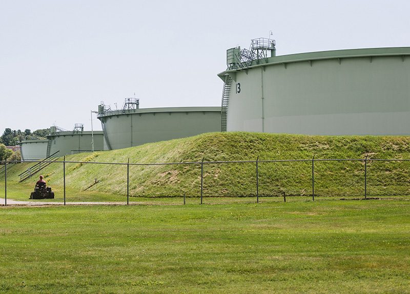 Oil storage tanks behind a chain-link fence on the Hill Street tank farm in South Portland